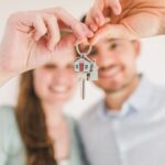Young couple holding keys to their new home, symbolizing a fresh start and investment in real estate.